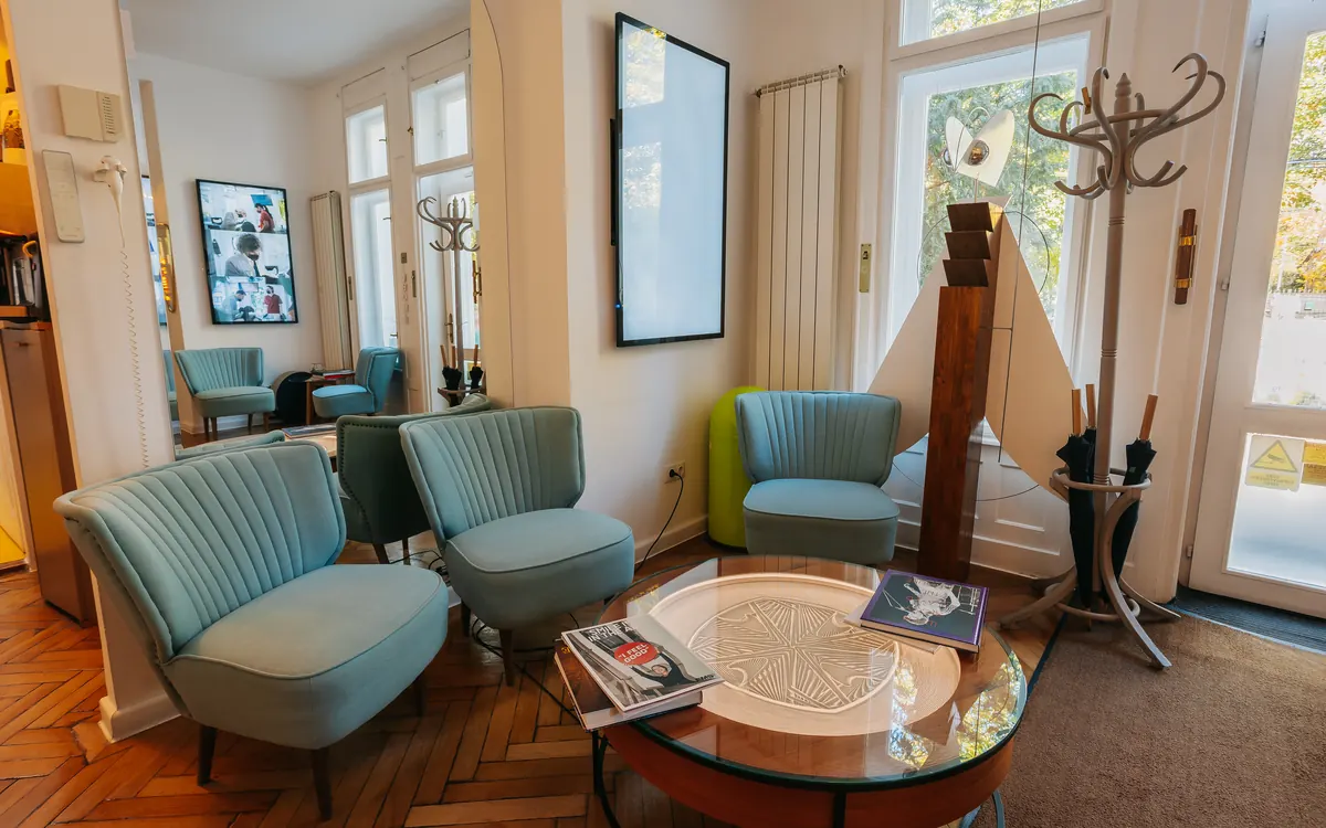Sala de așteptare D'Institute, cu fotolii turcoaz, măsuță și ferestre mari
