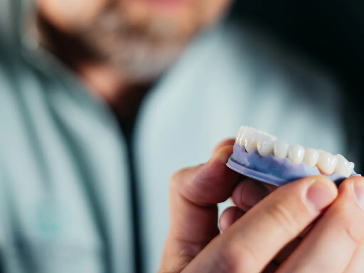 Medic D'Institute ținând în mână un model dentar cu lucrarea finală